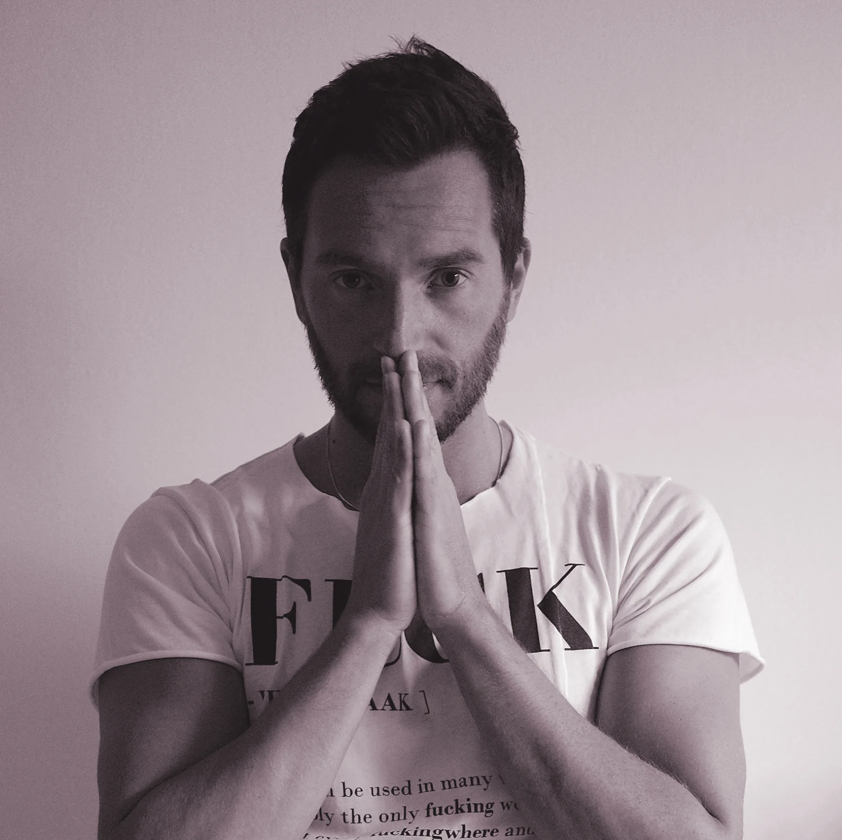Italian DJ and producer INVE looking the camera with his hands together in prayer, B & W image.