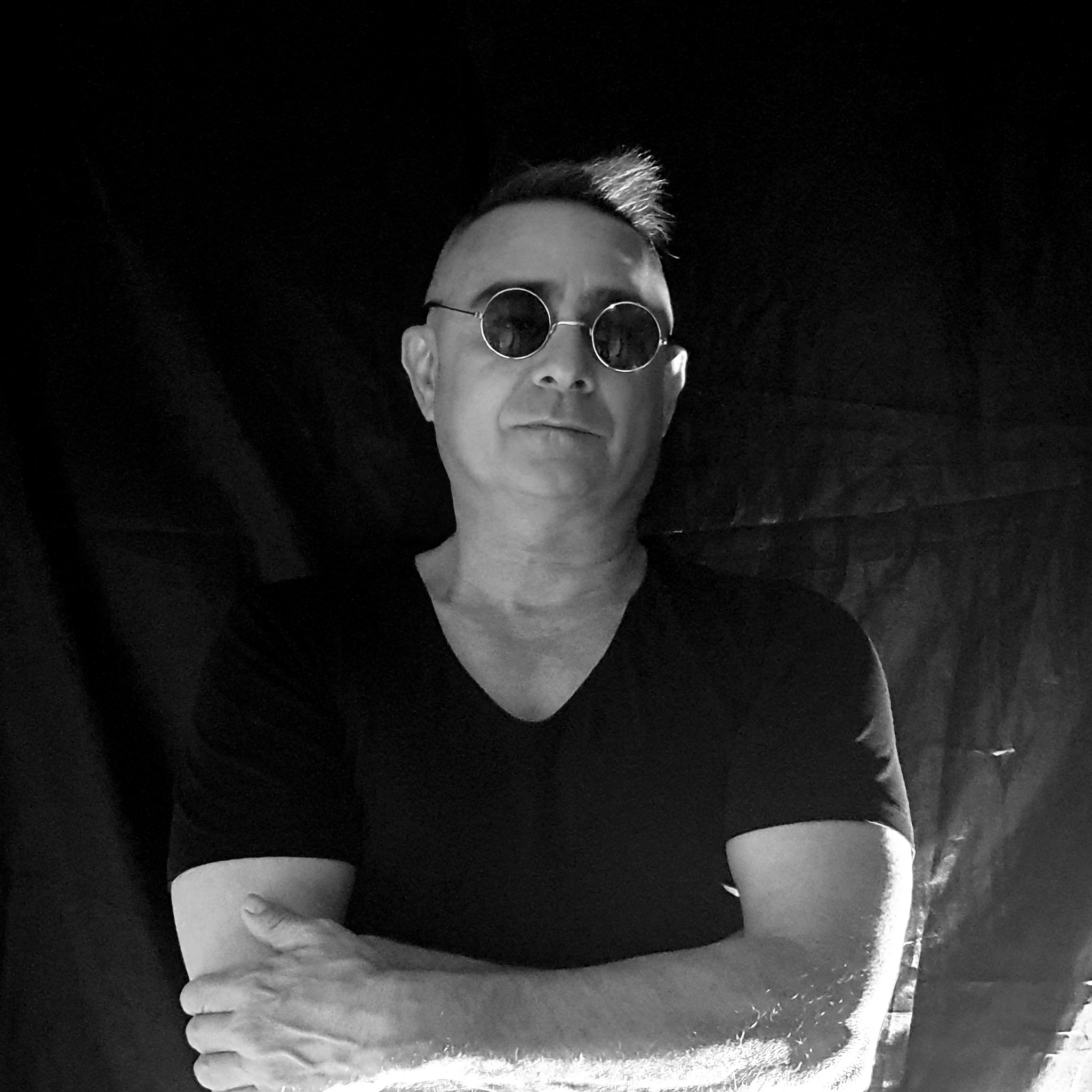 Israeli DJ and producer Choopie standing with arms crossed wearing sunglasses, black and white image.