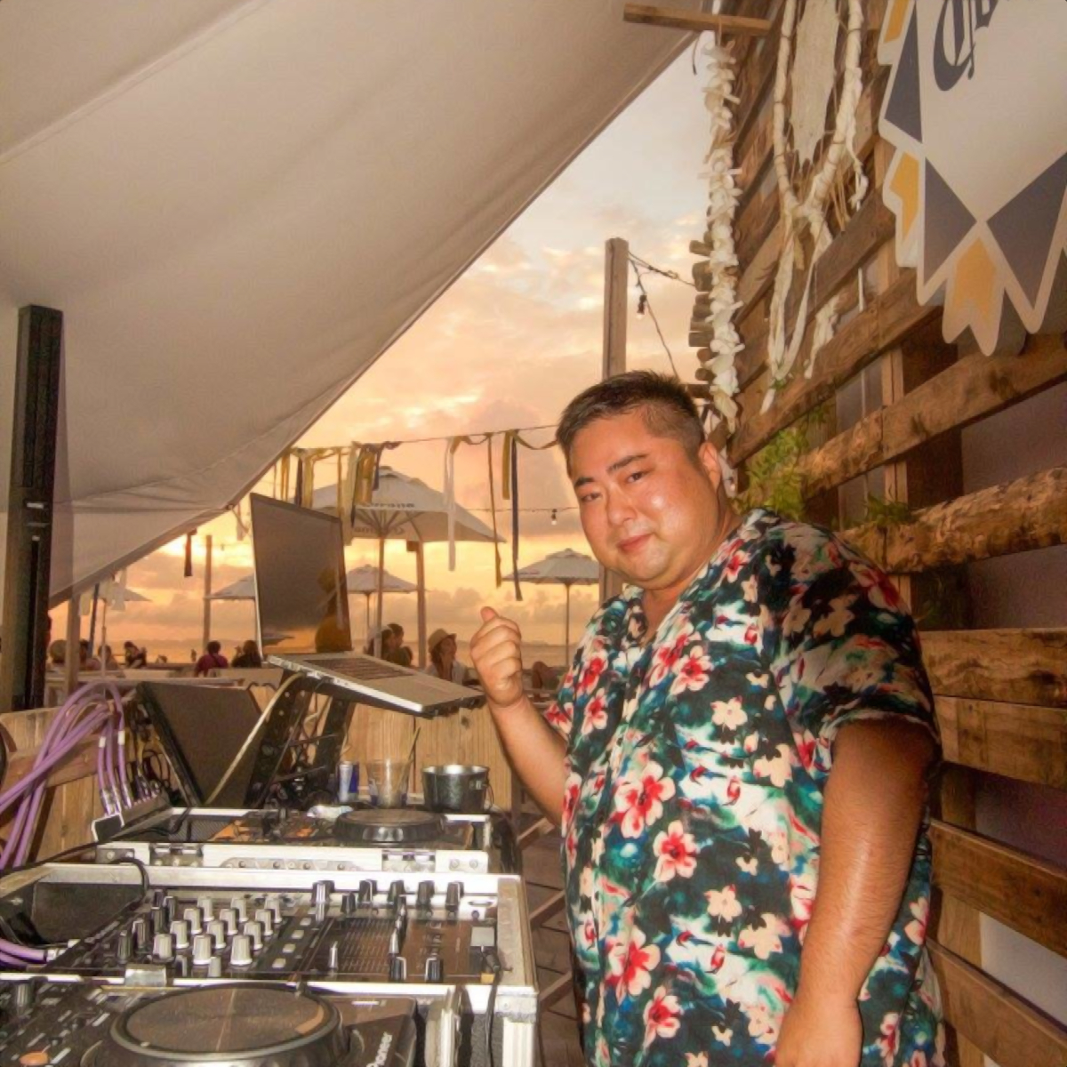 Japanese DJ Marcy smiling at camera with beach in backgroubnd, colour image.