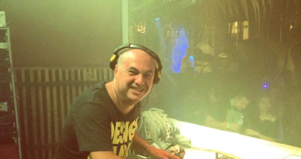 Italian DJ and Producer Marco Mei standing in DJ Booth looking at camera during event, colour image