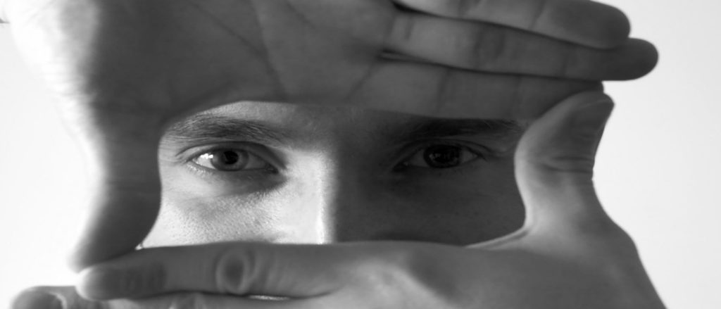 Italian DJ and Producer INVE looking through a rectangle mad with his hands, black and white image.