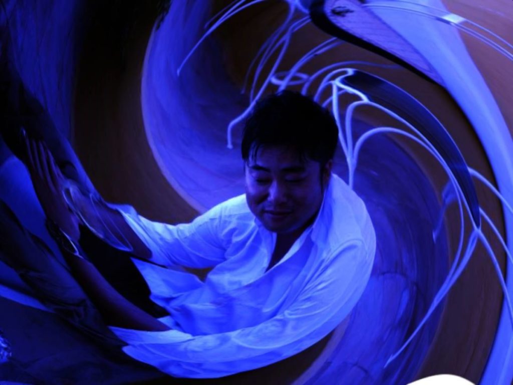 Japanese DJ and promoter DJ Marcy in a swirl shot in Black and white with a blue tinge.