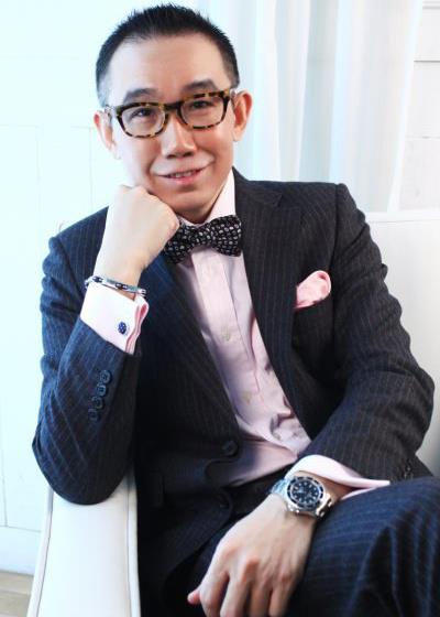 Taiwanesxe DJ and presenter Louis Chen sittiing in a chair with his chin on his right fist and smiling at the camera, colour image.