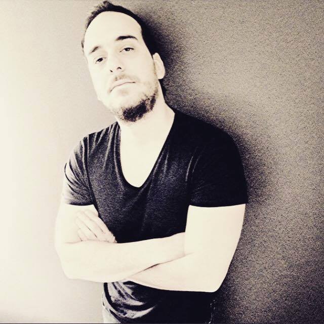 Greek DJ and Producer Simos Tagias standing with arms crossed looking at camera, black and white image.