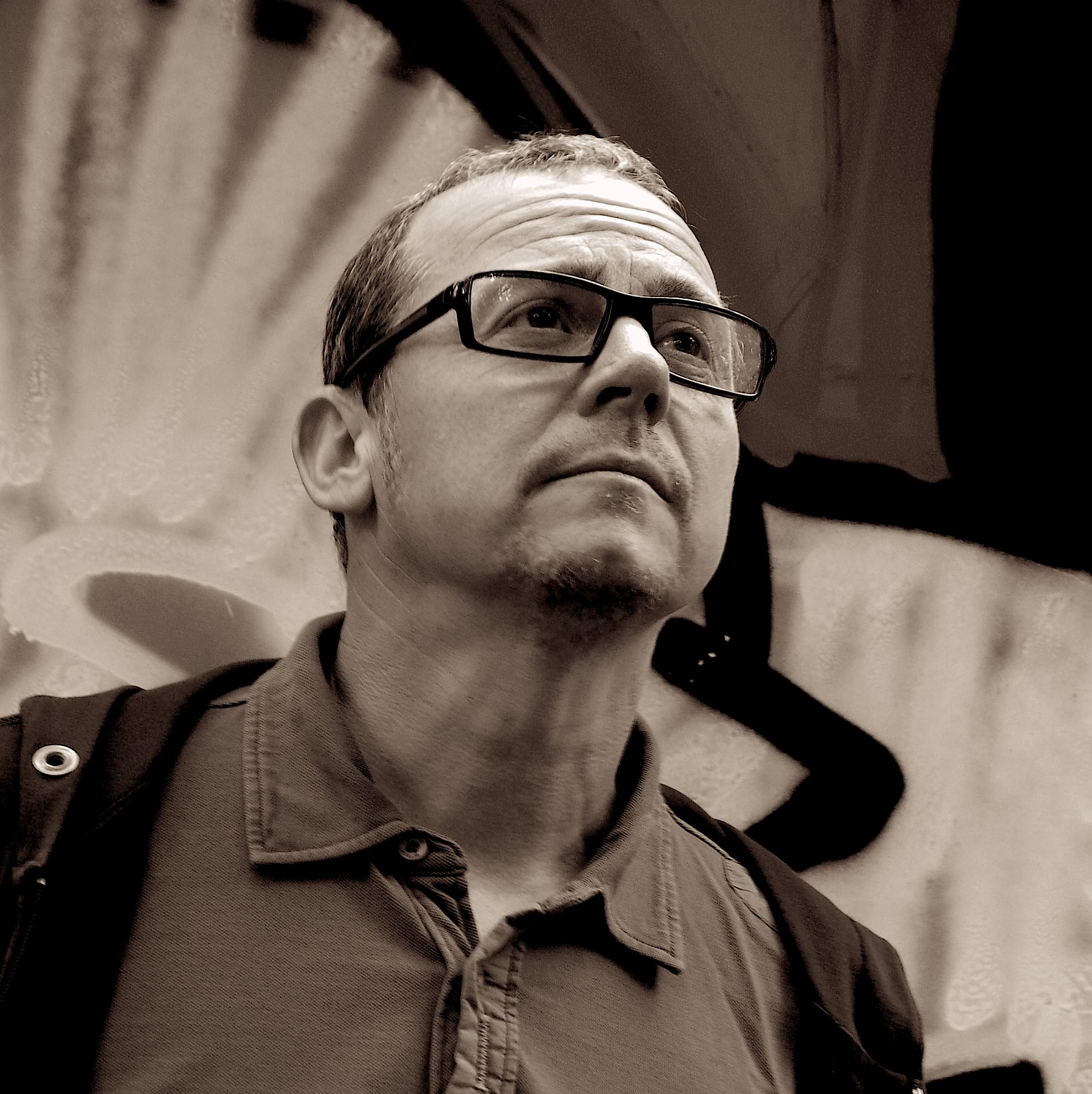 PhiPhi a.k.a Philippe Toutlemonde standing looking over to left, black and white image with a tinge.