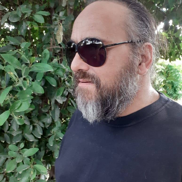 Argentinian DJ and producer Falso Simulacro standing wearing sunglasses whilst looking right, colour image.