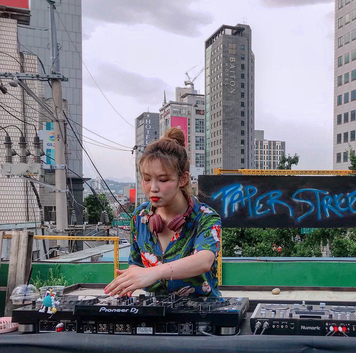 South Korean DJ PLOI performs behind a Pioneer DJ setup on a rooftop in Seoul, representing her Funky House, Disco House and Soulful House sound.