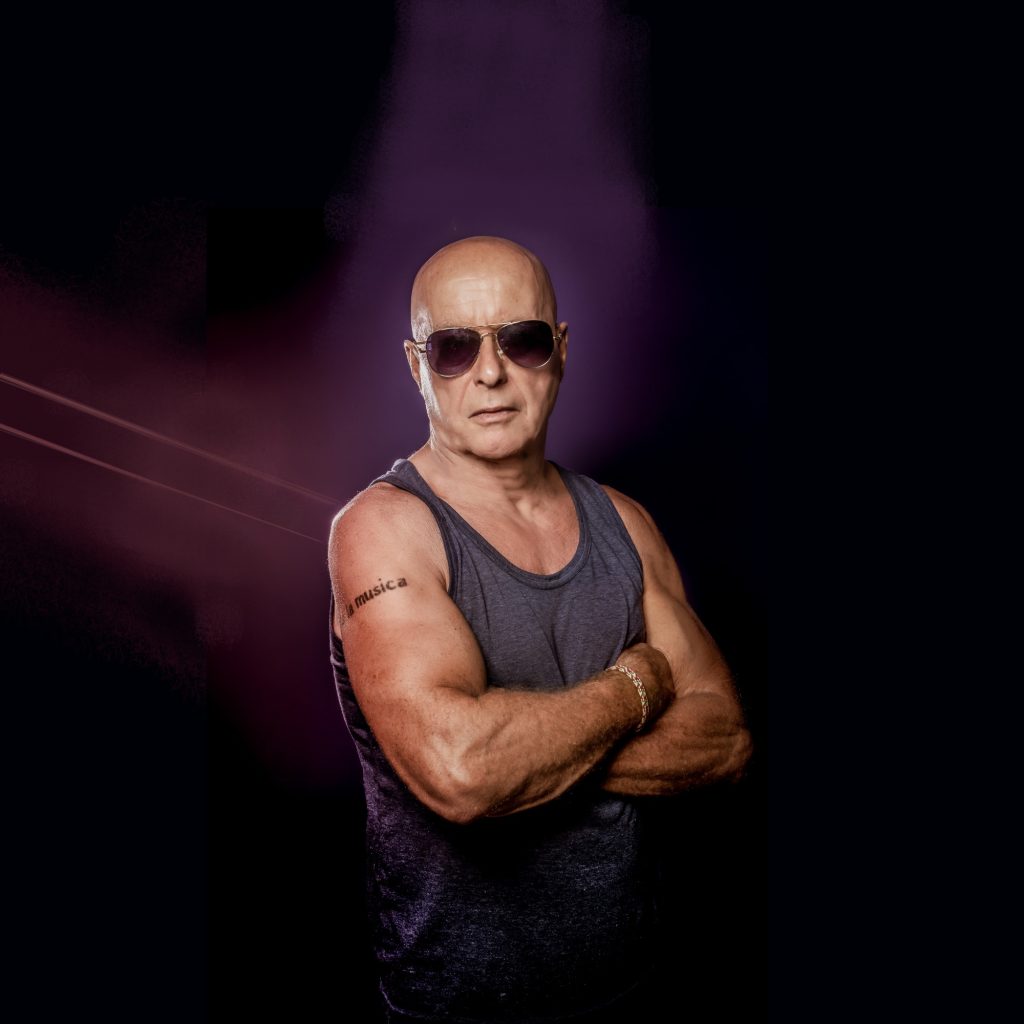 British DJ and producer Graham Gold standing with arms crossed wearing sunglasses, colour image.