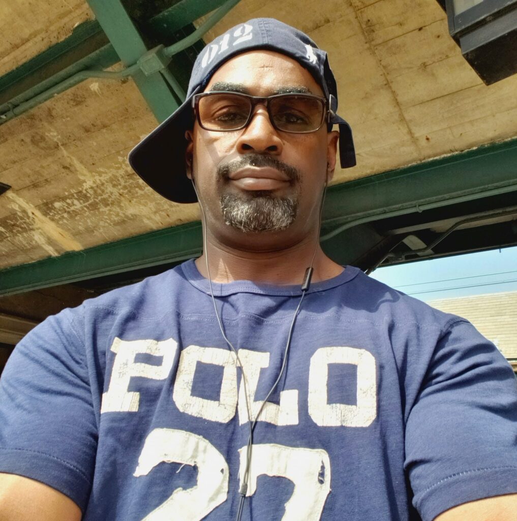 Hip Hop artist El Da Sensei wearing glasses and a sideways cap.