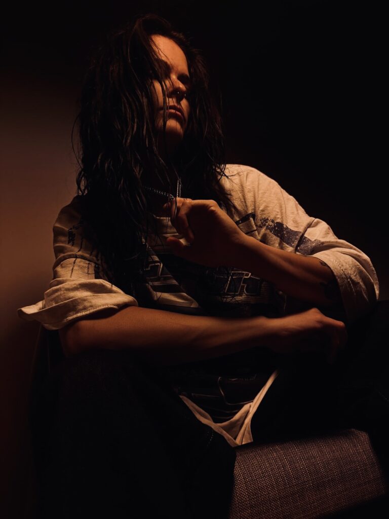Singer-songwriter Alyssa Thomas in a dark, warmly lit portrait, featured on REYUS track Around You.