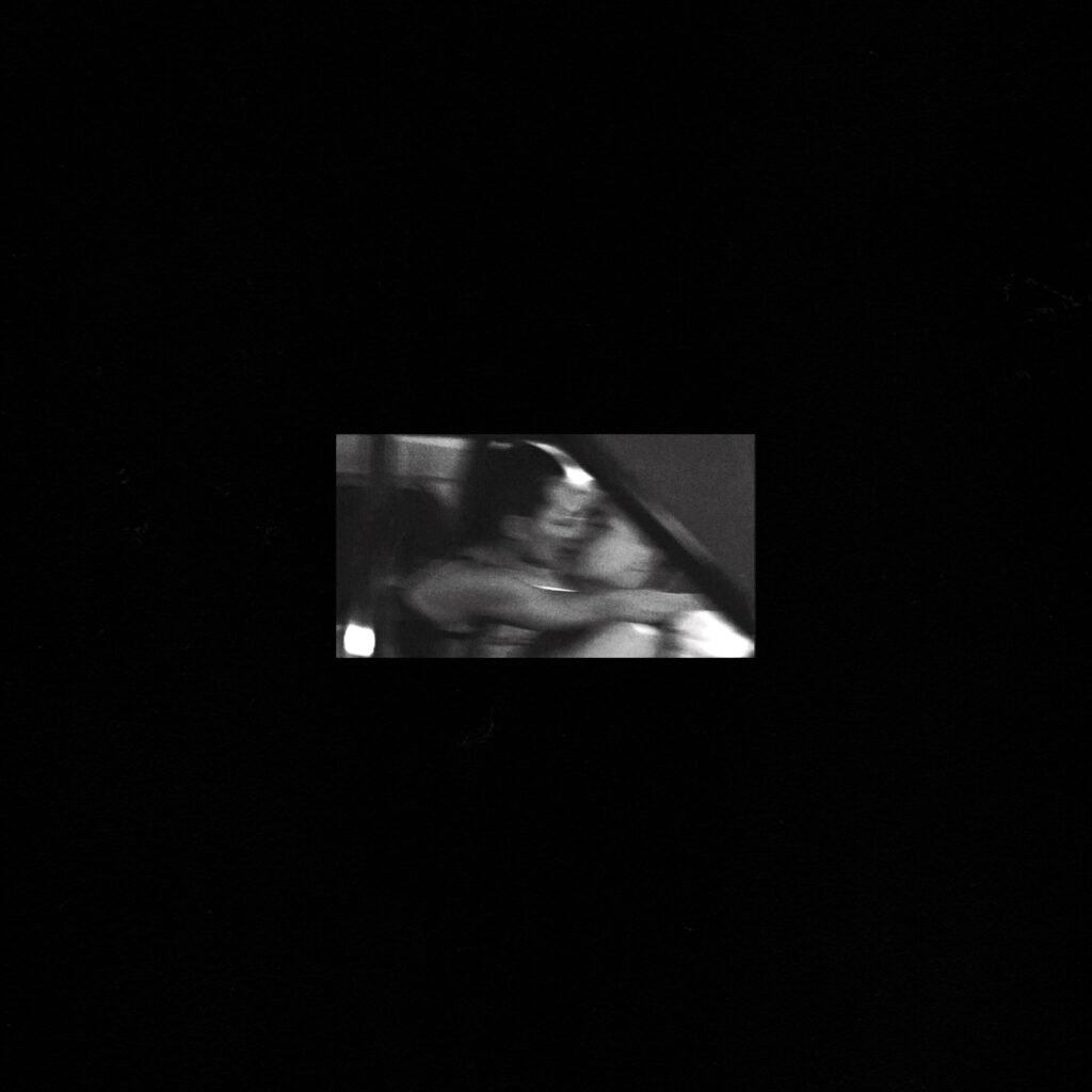 Artwork for REYUS debut album I’m Listening, featuring a blurred black-and-white image of two people embracing against a black background.