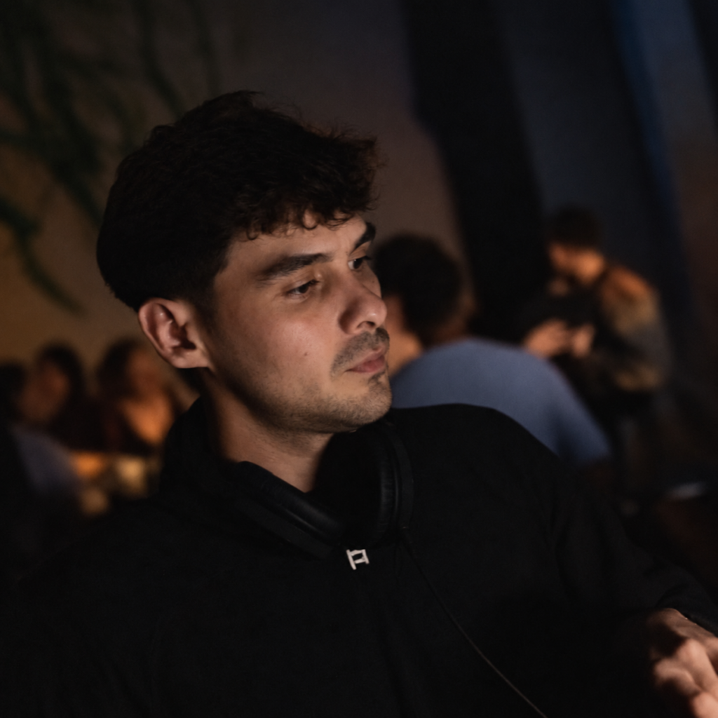 Progressive House DJ Hiram Scoffield wearing headphones during a late-night performance.